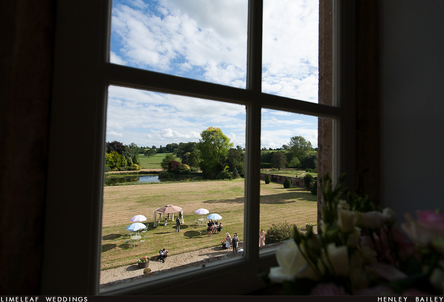 Guests gather on the lawn at Brympton D'evercy as seen out of a window from Brympton House