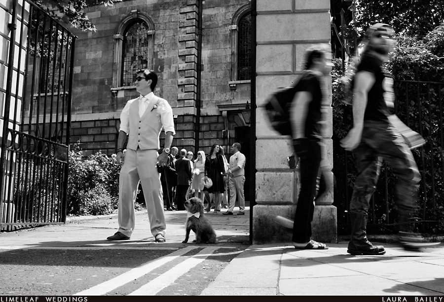 Usher and the bride and grooms dog wait at the church gate in London as tourists pass them by 