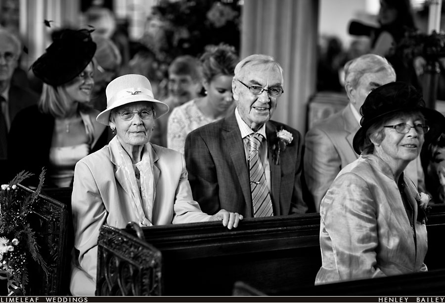 Wedding guests smile as they wait in church for the ceremony to start