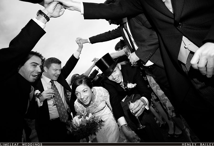 Couple head to their wedding reception through an arch of the guests