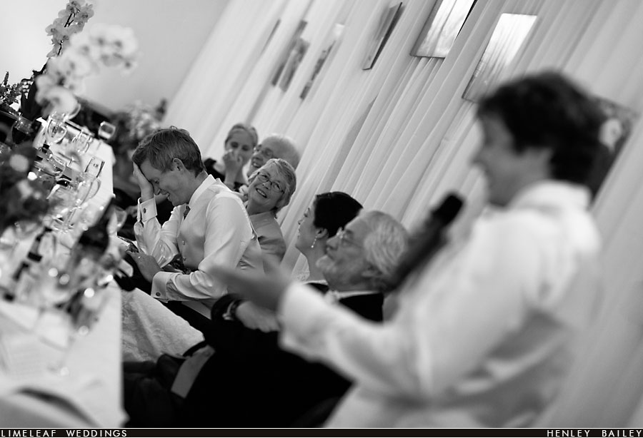 Groom holds his head in his hands as his best man does a wedding speech